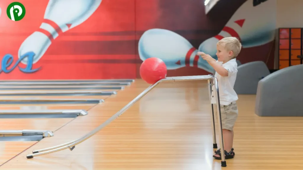 A child rolling a bowling ball down a brightly lit lane in a bowling alley
