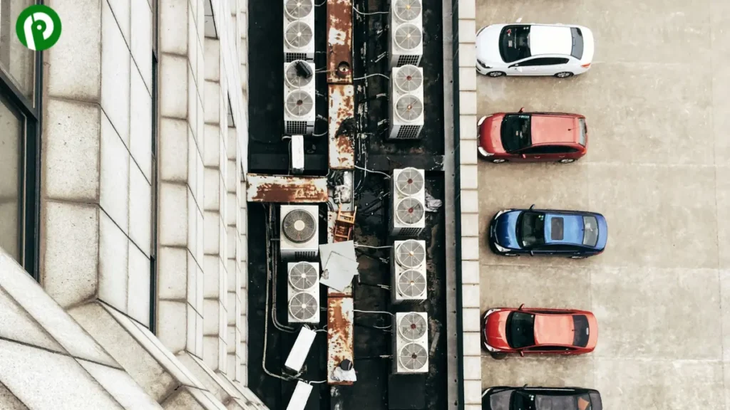Overhead view of compact cars parked next to a building with HVAC units on the roof.
