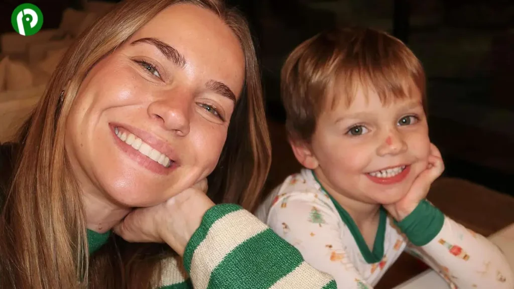 A young woman holding a small child in a cozy, candid moment, both smiling warmly.