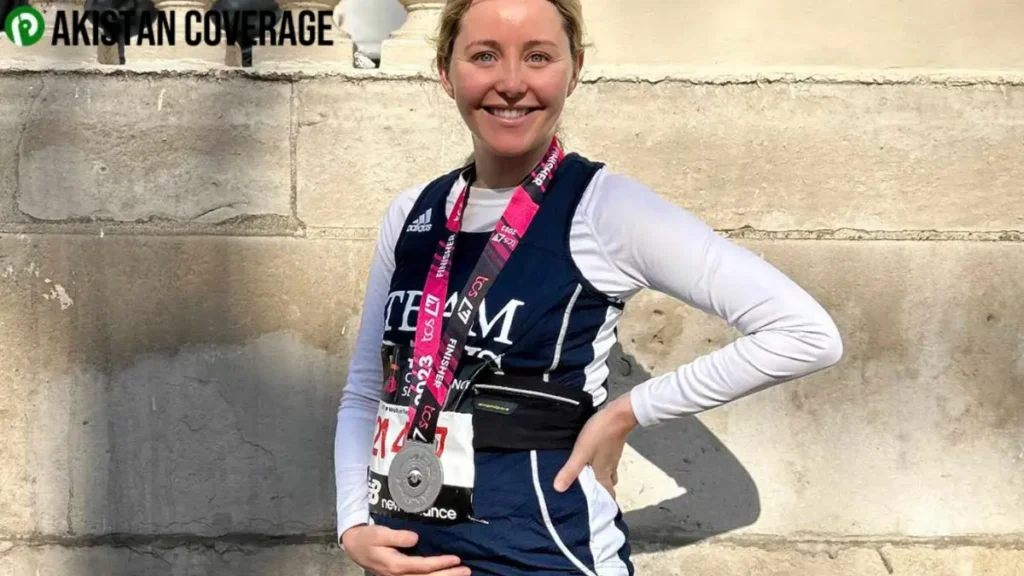 Smiling woman after completing a race in 2023, wearing a finisher medal and cradling her baby bump in a proud, joyful moment.