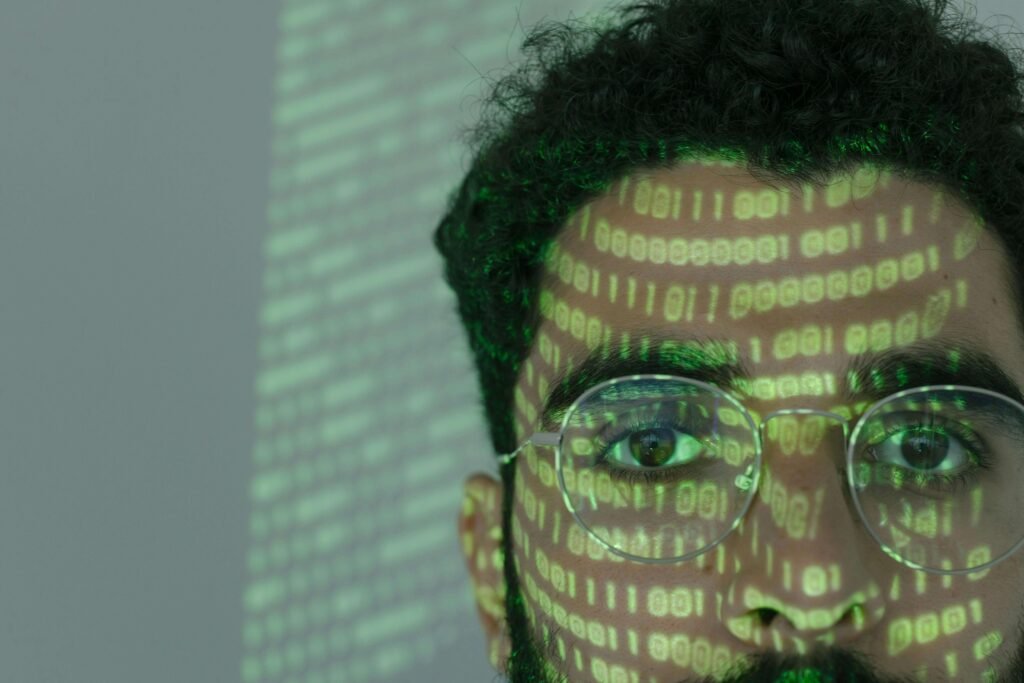 Close-up of a man's face with green binary code projected on his skin and glasses, symbolizing AI web crawling, machine learning, and futuristic data analysis in 2025.