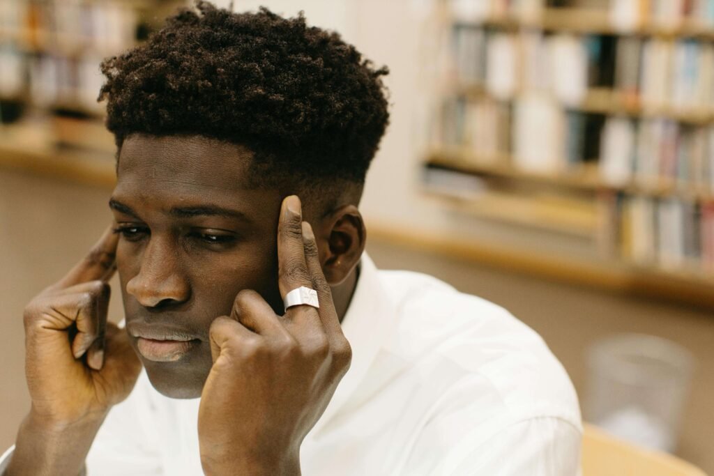 A person sitting with fingers on temples, reflecting deeply in a moment of concentrated thought