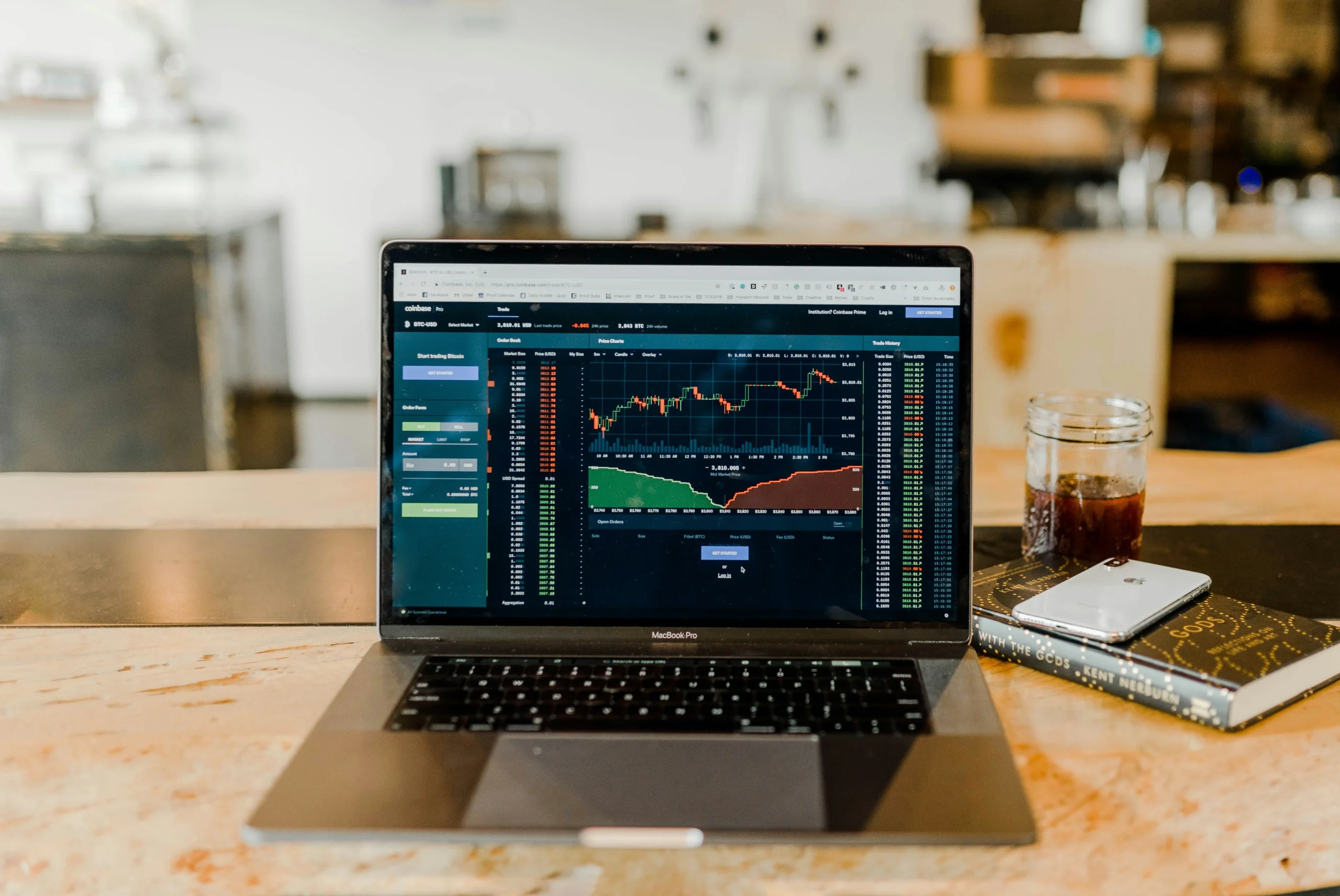 Laptop showing crypto trading dashboard with strategy book and phone on a desk, symbolizing Biitland.com’s future-focused crypto investment tools and strategies in 2025.