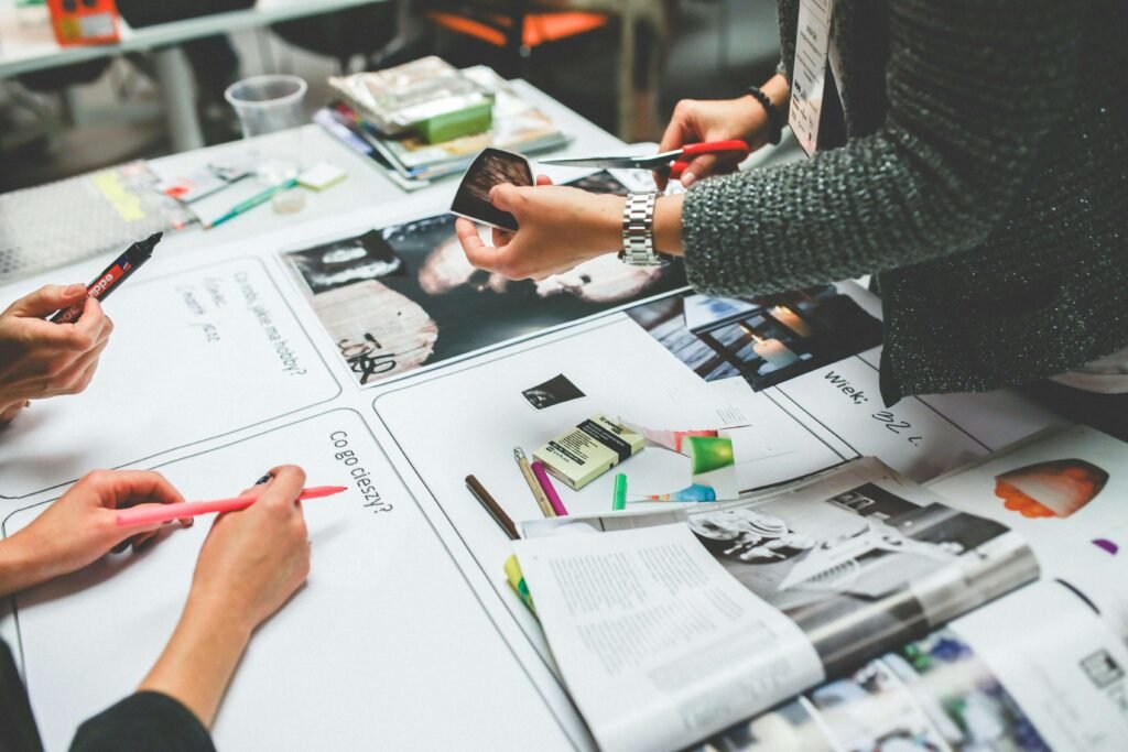 Girl designing with scissors in hand while team assists her in creative workspace