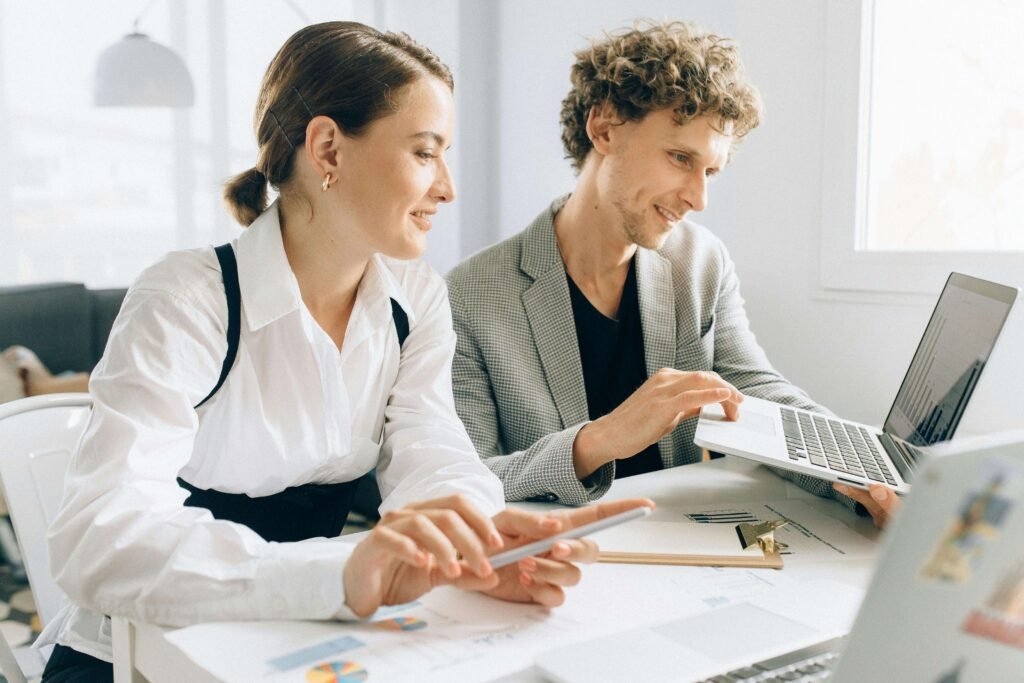 Two professionals collaborating using a laptop and tablet while analyzing performance charts — ideal representation of the Troozer.com onboarding process.