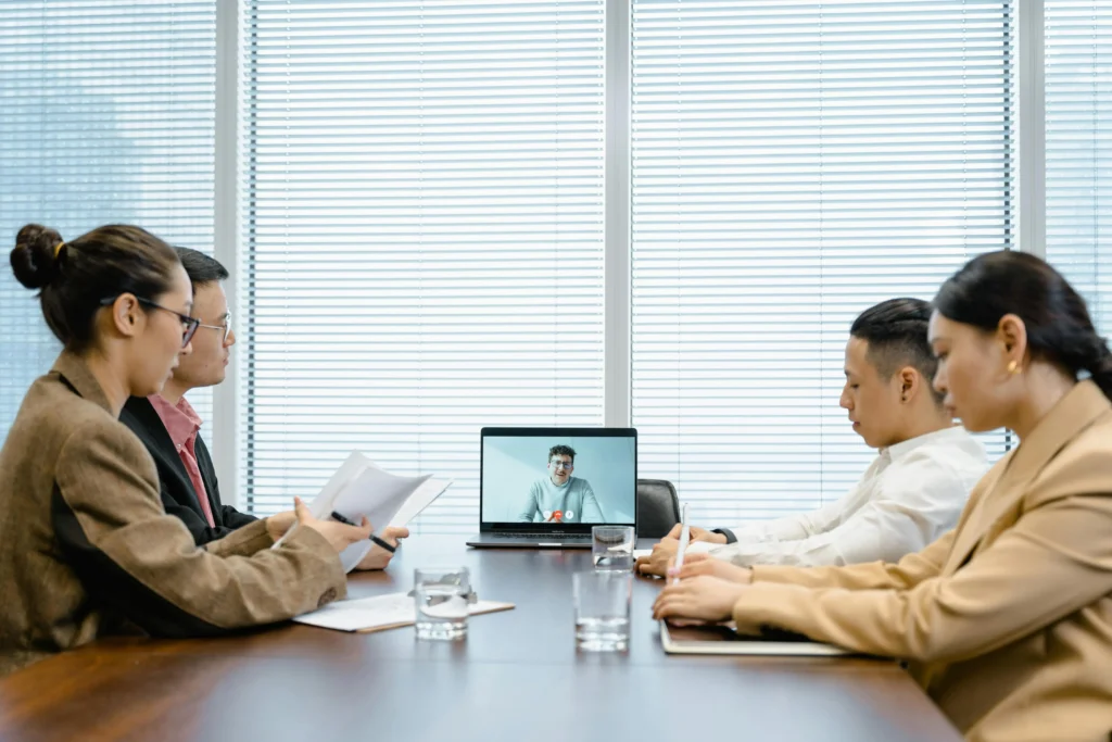 Office workers using EWMagWork workplace management and conflict resolution tools during a hybrid team meeting.
