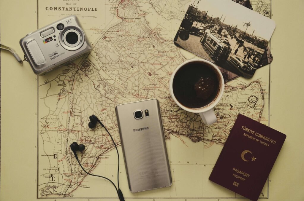 Flat lay showing a travel map, smartphone, passport, camera, and coffee—symbolizing the travel, tech, and lifestyle themes of Style Inventure.