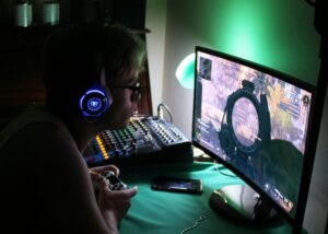 Gamer wearing futuristic headset playing a shooter game on a curved monitor with mod console and lighting, representing 2025 LCFGameNews reviews and trends.