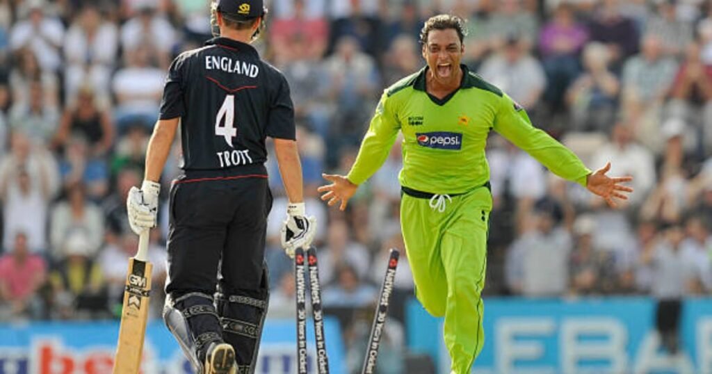 Shoaib Akhtar celebrating on the cricket field in a green Pakistan jersey with arms outstretched.