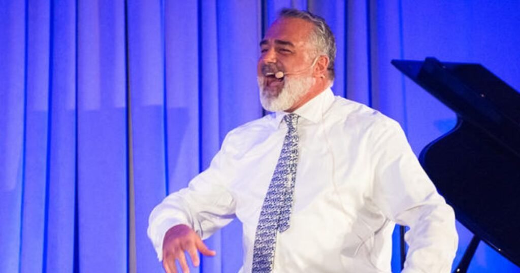 Kenny Polcari giving a speech about his education qualifications