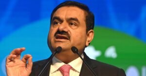 Gautam Adani speaking at a public event with microphones in front of him
