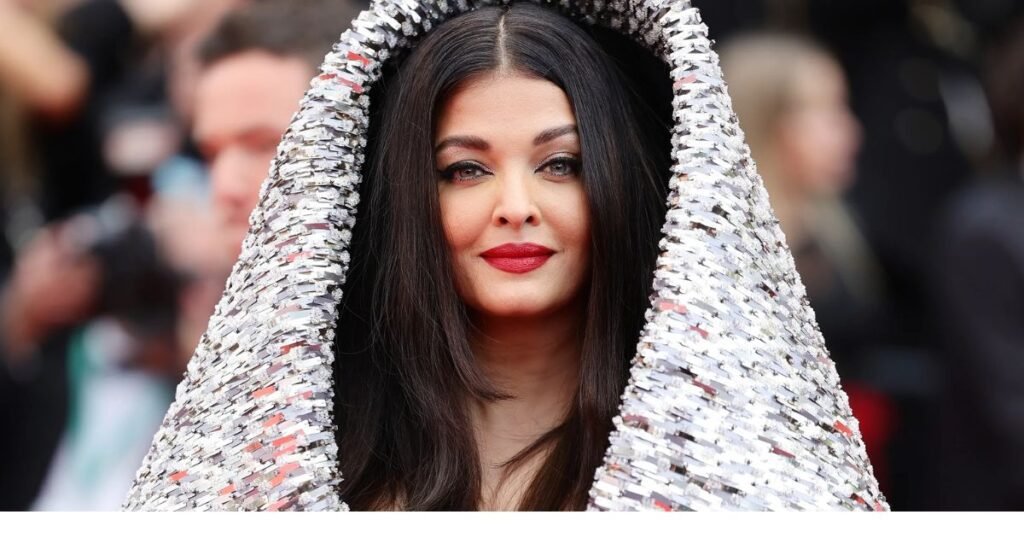 Aishwarya Rai wearing a glamorous silver-sequined outfit with a hood, attending a high-profile red carpet event.