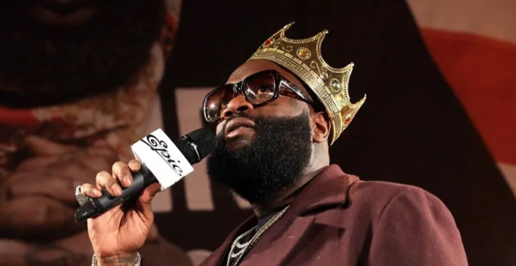 Rick Ross with crown holding microphone during event