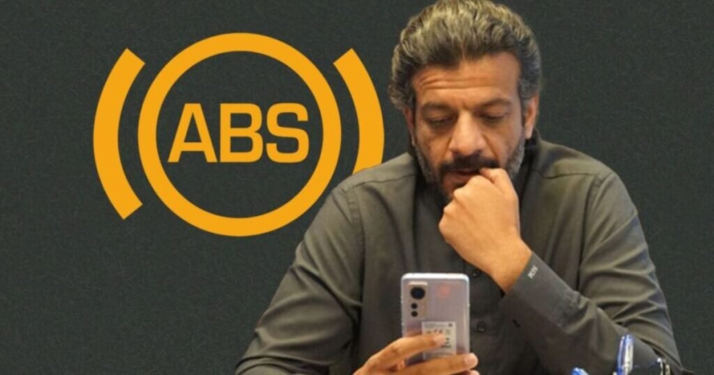 Suneel Munj looking at his phone with ABS logo in the background