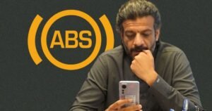 Suneel Munj looking at his phone with ABS logo in the background